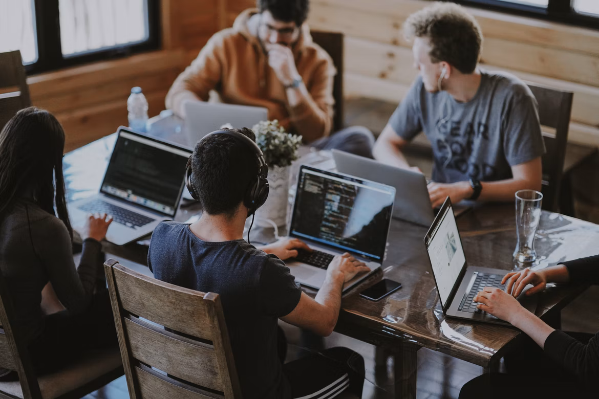A group of people sitting together at a table, probably working together.