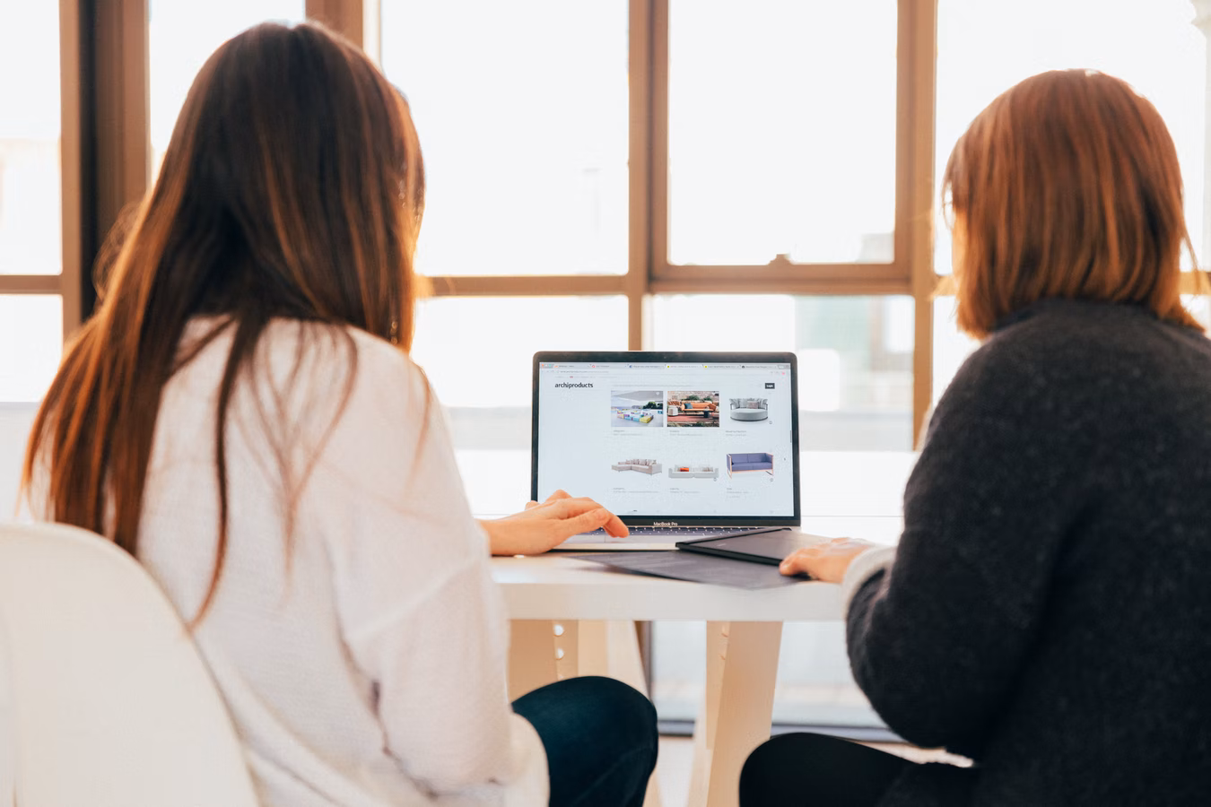 Two women working staring at a laptop, probably working together.